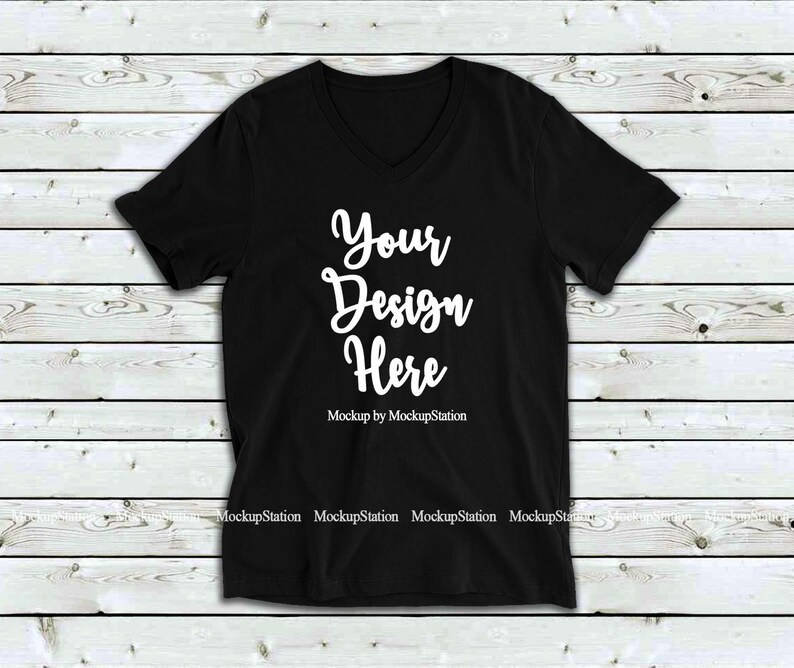 May include: Black v-neck t-shirt mockup with the text "Your Design Here" on a white wooden background.
