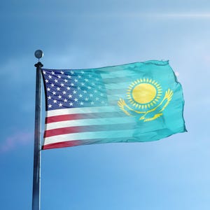May include: A flag combining the design of the United States and Kazakhstan, displayed against a bright blue sky. The American flag is on the left, blending into the Kazakh flag on the right.