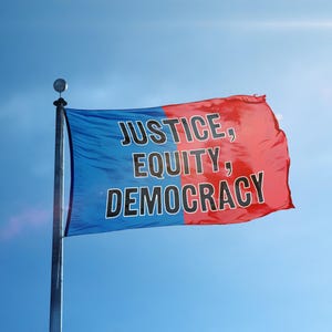 Könnte beinhalten: Eine Flagge mit blau-rotem Farbschema weht im Wind vor einem klaren blauen Himmel. Auf der Flagge stehen die Worte "JUSTICE, EQUITY, DEMOCRACY" in fetten, schwarzen Großbuchstaben. Die Flagge ist an einer silbernen Stange befestigt.