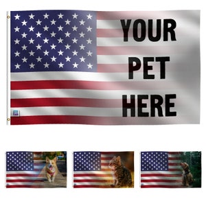 May include: A customizable American flag with the text "YOUR PET HERE" printed on the right side. The flag is red, white, and blue with a field of stars on the left side. The flag is shown with three different images of pets, a dog, a cat, and a dog, in the background.