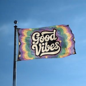 Puede incluir: Una bandera rectangular con las palabras "Good Vibes" en una fuente retro. La bandera tiene un diseño psicodélico colorido con un patrón repetitivo de formas curvas en tonos de morado, verde, amarillo y azul.