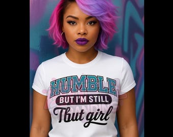 May include: A white t-shirt with the text "HUMBLE but I'm STILL That girl" in teal, black, and white. The person in the image has pink and purple hair and purple lipstick. The background is a colorful graffiti wall.
