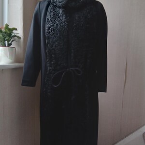 May include: A black wool coat with a black fur collar and a tie at the waist.