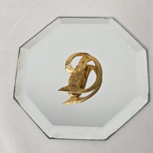 May include: A gold-toned abstract swirl brooch with a textured finish.