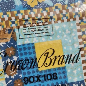 May include: A blue and brown fabric with a floral pattern. The fabric is labeled "Crown Brand" and has a size of 90x108 inches. The label also states that the fabric is a blend of 66% polyester and 35% percale cotton and is non-iron.