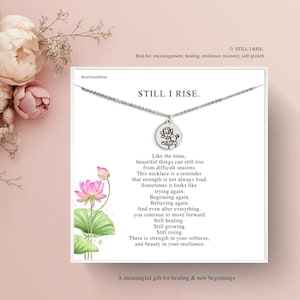 May include: A silver necklace with a round pendant featuring a lotus flower design. The card reads "STILL I RISE" with an inspirational message. The background includes pink flowers and text.