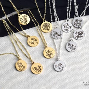 May include: A collection of gold and silver necklaces with round pendants, each engraved with a different floral design. The necklaces have delicate cable chains. The text "Blush Gold Rose" is in the upper left corner. The text "Cable Chain Style Adjustable 17"-20"" is in the lower right corner.