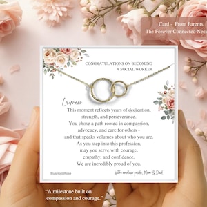 May include: A gold-colored necklace with two interlocking circles, presented on a card with floral accents. The card reads "Congratulations on Becoming a Social Worker" and includes a personalized message. The necklace is a thoughtful gift.