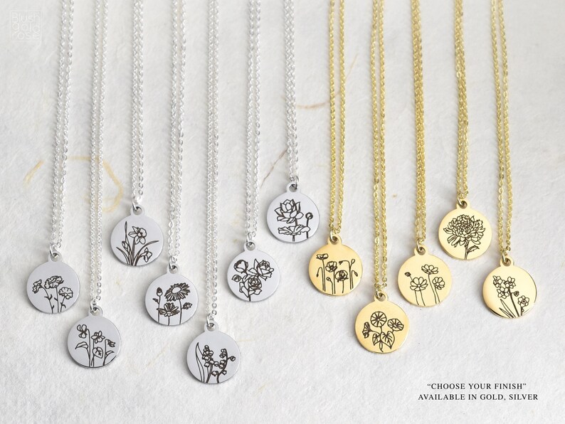 May include: A collection of necklaces with round pendants, each featuring a different floral design. The necklaces are available in gold and silver finishes. The pendants are suspended from delicate chains, showcasing detailed botanical illustrations.