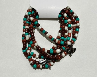 Può includere: Un set di sei braccialetti con perline marroni, bianche e turchesi. Ogni braccialetto ha un ciondolo a forma di libellula.