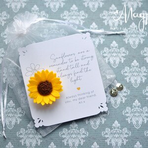May include: A yellow felt sunflower attached to a white card with a decorative edge. The card has text that reads "Sunflowers are a reminder to be strong, stand tall and always find the light." The card is in a sheer bag.