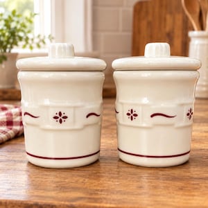 May include: Two off-white ceramic canisters with matching lids, each featuring a raised basket-weave texture around the center and a dark red decorative pattern consisting of small floral motifs and horizontal wavy lines.