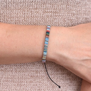 Peut inclure: Un bracelet en perles color&eacute;es avec un cordon noir. Le bracelet pr&eacute;sente une vari&eacute;t&eacute; de couleurs, notamment le bleu, le rouge, le blanc et le noir.