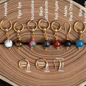 Peut inclure: Boucles d'oreilles dorées avec des perles de pierres précieuses variées : howlite, œil de tigre, tourmaline, labradorite noire, agate rouge, onyx noir mat et jade apatite bleue. Dimensions : 10mm intérieur, 12mm intérieur, et crochet de 17mm.