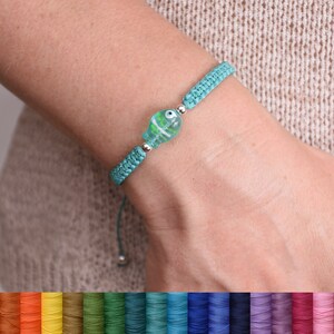 May include: A turquoise braided bracelet with a silver charm featuring a blue and green glass eye. The bracelet is adjustable with a sliding knot. The image shows a variety of colors for the bracelet cord.