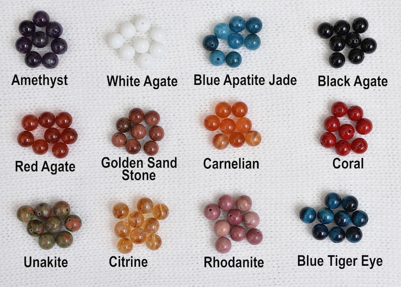 May include: A collection of gemstone beads in various colors, including amethyst, white agate, blue apatite jade, and black agate. Other stones include red agate, golden sand stone, carnelian, coral, unakite, citrine, rhodonite, and blue tiger eye. Each stone is labeled.