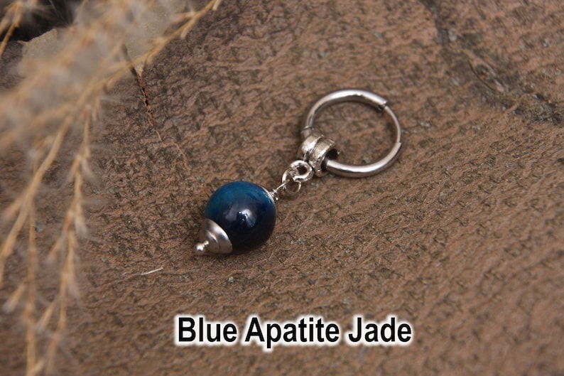 May include: A single silver hoop earring with a dangling blue apatite jade bead. The bead is a deep blue color with a silver cap. The text "Blue Apatite Jade" is displayed at the bottom of the image.