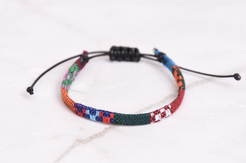 Peut inclure: Un bracelet tiss&eacute; color&eacute; avec une fermeture en cordon noir r&eacute;glable. Le bracelet pr&eacute;sente une vari&eacute;t&eacute; de couleurs, notamment le rouge, l'orange, le jaune, le vert, le bleu et le violet.