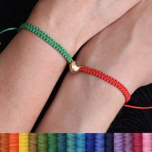 Peut inclure: Deux bracelets d'amitié avec un charme en forme de cœur doré. Les bracelets sont faits de cordon vert et rouge. Le cordon est disponible dans une variété de couleurs.