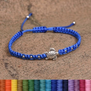 May include: A blue braided bracelet with a silver turtle charm and silver beads. The bracelet is adjustable and can be worn on the wrist or ankle. The bracelet is available in a variety of colors.