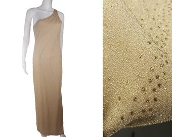 May include: A beige, one-shoulder evening gown. The floor-length dress is embellished with small, sparkling accents. The fabric has a subtle texture, and the dress drapes smoothly. The gown is displayed on a mannequin.
