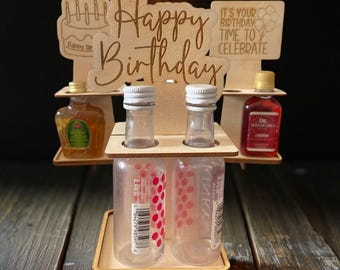 Könnte beinhalten: Ein Holzständer mit einem "Happy Birthday"-Schild und vier Fächern für Miniaturflaschen. Der Ständer ist mit einem Kuchen und Ballons verziert. Es ist dein Geburtstag, Zeit zum Feiern!