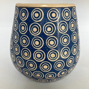 Pode incluir: Um conjunto de três canecas de cerâmica com acabamento fosco e salpicado. As canecas são em tons de creme, cinza claro e cinza escuro. Cada caneca tem um design simples e minimalista.