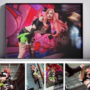 Op de afbeelding: Een ingelijste print met een vrouw in een cosplay-outfit met roze haar, poserend voor graffiti-kunst. Ze houdt een groen pluche speelgoed vast. De achtergrond heeft een vervaagd effect.