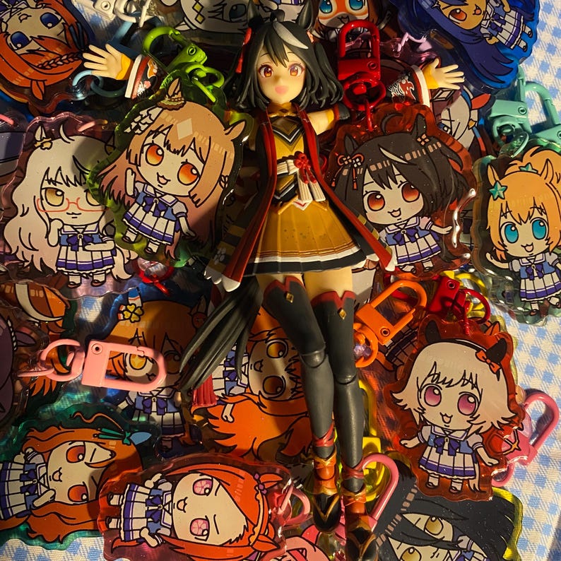 May include: A collection of anime-style keychains and a figurine. The keychains feature various cartoon characters with large eyes and colorful outfits. The figurine is of a character in a yellow and red outfit. The keychains have various colored clasps.