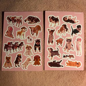 May include: Two sheets of stickers featuring various dog breeds in different poses. The stickers are on a pink background and include text that reads "NINTENDOGS 1.0" and "NINTENDOGS 2.0". The stickers are in a cartoon style.