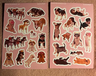 May include: Two sheets of stickers featuring various dog breeds in different poses. The stickers are on a pink background and include text that reads "NINTENDOGS 1.0" and "NINTENDOGS 2.0". The stickers are in a cartoon style.