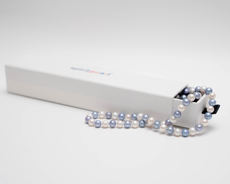 May include: A white box with the text "Aspire Pearl" on the top, with a strand of white and lavender pearls spilling out of the box.