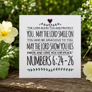 May include: A square white card featuring black printed text that reads: THE LORD BLESS YOU AND PROTECT YOU. MAY THE LORD SMILE ON YOU AND BE GRACIOUS TO YOU. MAY THE LORD SHOW YOU HIS FAVOR AND GIVE YOU HIS PEACE. NUMBERS 6:24-26, with a purple heart.