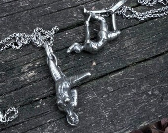 Op de afbeelding: Twee zilveren kettingen met gedetailleerde menselijke figuur hangers. De hangers zijn in verschillende poses, één staat en de andere is in een yoga pose.