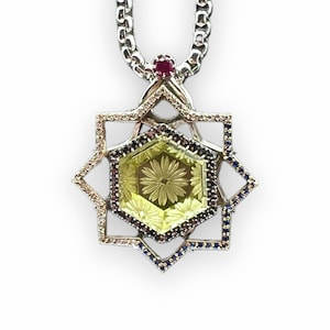 Puede incluir: Un collar de cadena de plata con un colgante que presenta una piedra preciosa amarilla rodeada de un marco de estrella de plata y azul.