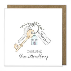 Puede incluir: Una ilustraci&oacute;n de acuarela de una llave de casa con una etiqueta que dice "Nuevo hogar" y un peque&ntilde;o amuleto de casa. La tarjeta dice "Felicidades Shaun, Lottie y Sammy".