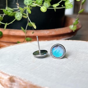 May include: A pair of silver stud earrings with a blue and white butterfly wing design.