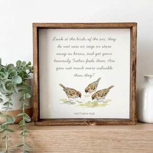 May include: A wooden framed sign featuring a watercolour painting of three small birds. The sign includes the text "Look at the birds of the air..." and "Matthew 6:26". The frame is a dark brown colour.