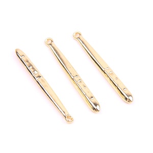 Puede incluir: Tres herramientas de metal de color dorado con una superficie texturizada y un bucle en la parte superior. Las herramientas están dispuestas en una fila sobre un fondo blanco.