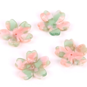 May include: Four pink and green flower-shaped beads with a hole in the center. The beads are made of a translucent material and have a marbled pattern.
