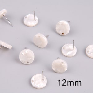 Puede incluir: Diez pendientes redondos blancos con postes plateados. Cada pendiente tiene un pequeño agujero en el centro. Los pendientes tienen un diámetro de 12 mm.