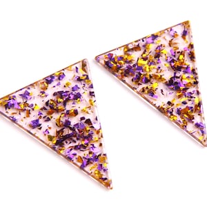 May include: A pair of triangle-shaped earrings with a clear resin base filled with gold and purple glitter.