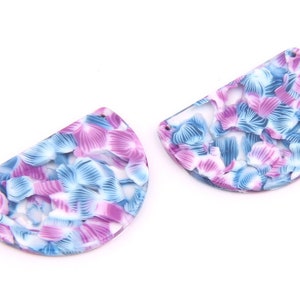 Puede incluir: Dos pendientes en forma de semicírculo con un patrón floral blanco, azul y rosa.