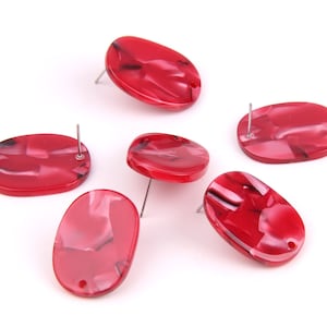 May include: Six red oval-shaped earrings with a marbled pattern and silver posts.
