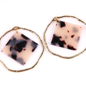 May include: A pair of gold hoop earrings with a square-shaped tortoiseshell-patterned pendant hanging from each hoop.