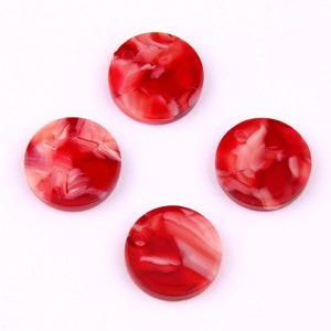 Puede incluir: Cuatro botones redondos de plástico marmoleado rojo y blanco.