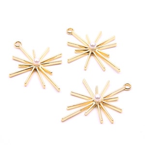 May include: Three gold starburst charms with a pearl in the center of each. The charms have a loop at the top for attaching to jewelry.