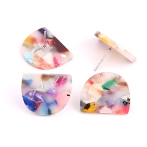 Puede incluir: Cuatro pendientes de botón abstractos y coloridos. Dos tienen forma de semicírculo y dos son semicirculares. Los pendientes tienen un cierre de poste y están hechos de un material moteado colorido con tonos de rosa, azul, verde y amarillo.