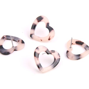 May include: Four pairs of heart-shaped earrings with a tortoiseshell pattern. The earrings are made of a light pink and brown plastic material.