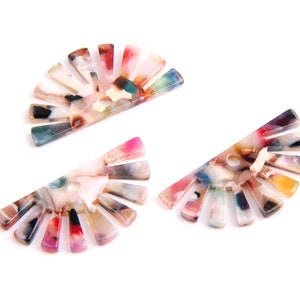 May include: Three colourful, semi-circular, plastic hair clips with a fan-like design. Each clip has a different colour pattern with shades of pink, blue, green, yellow, and brown.